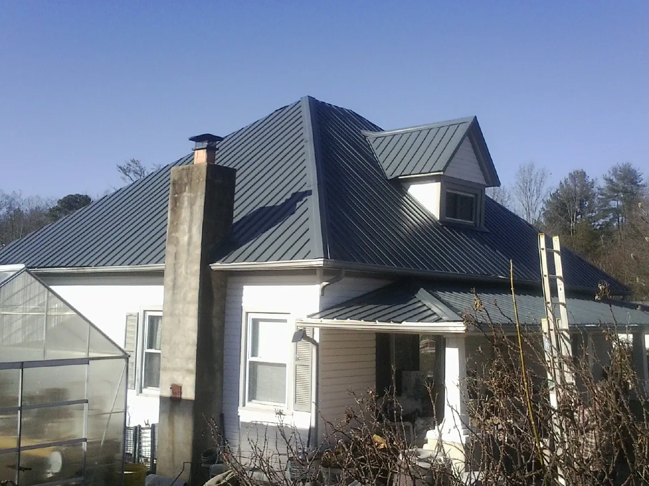 Dark blue standing seam metal roof on a white farmhouse with dormer — Slate & Tile Roof Repair by Roofing Brothers in Boalsburg