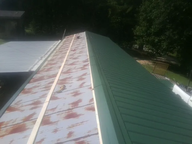 Old rusted panels beside newly installed green metal roofing — Wind Damage Roof Repair by Roofing Brothers in Boalsburg