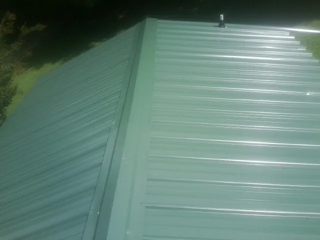 New green metal panels meeting at the ridge of a roof — Flat Roof Repair work by our crew in Boalsburg