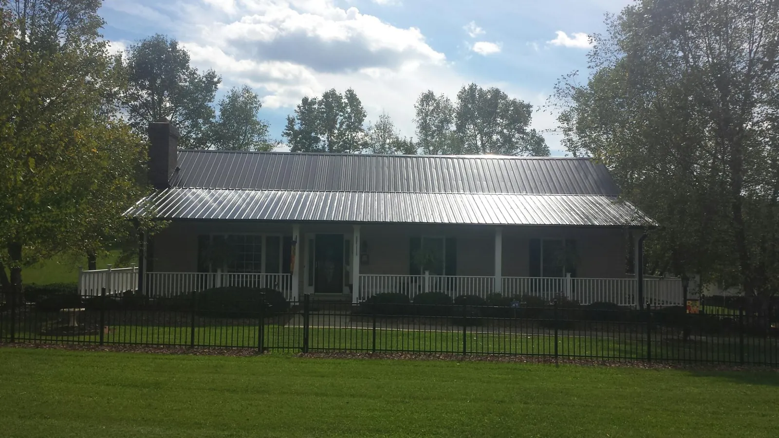 Gray metal roof on a brick ranch with a full width front porch — Gutter Guard Installation work by our crew in Boalsburg