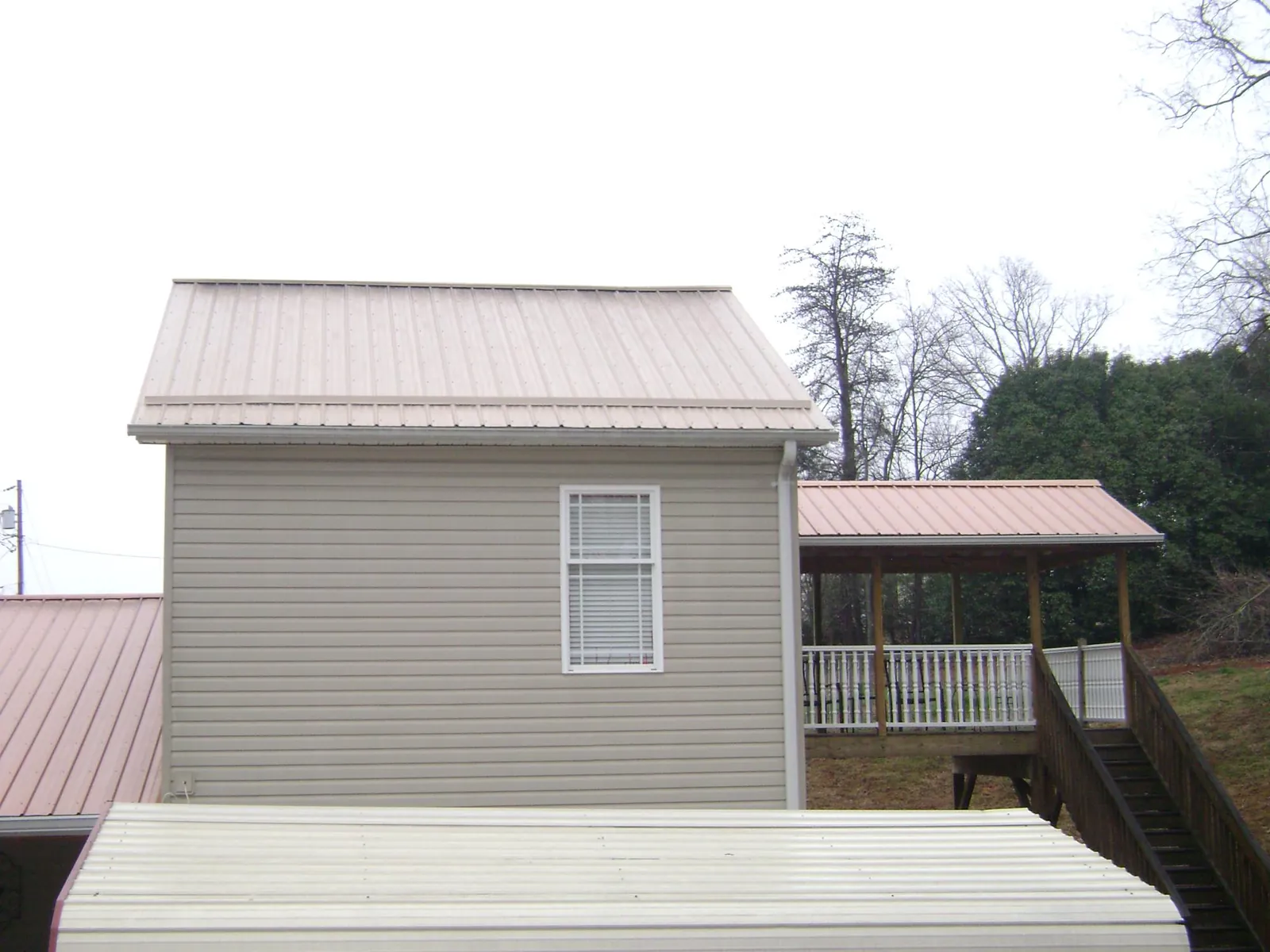 Tan metal roofs on a two story addition and attached porch, from a Roof Replacement job in Boalsburg