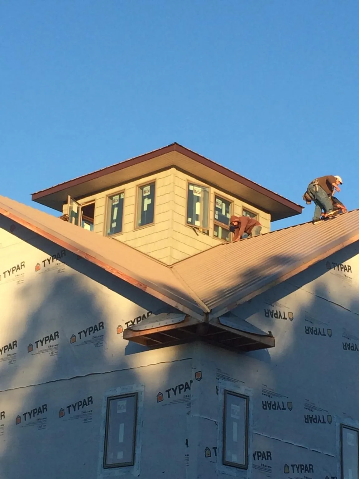 Roofers working around a rooftop cupola on a new metal roof at sunset — Roof Waterproofing in Boalsburg by Roofing Brothers
